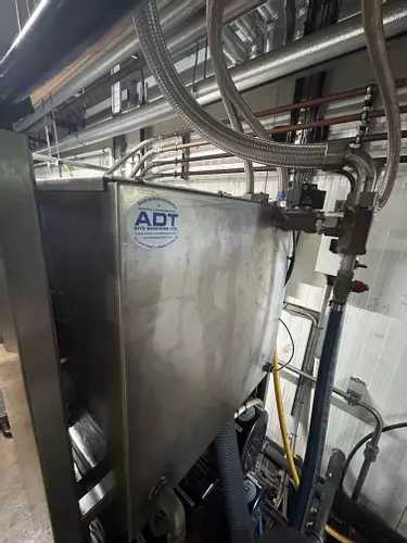 Rear view of custom stainless steel replacement tank installed on a Nilfisk Delta Booster multi-pump pressure washer system.